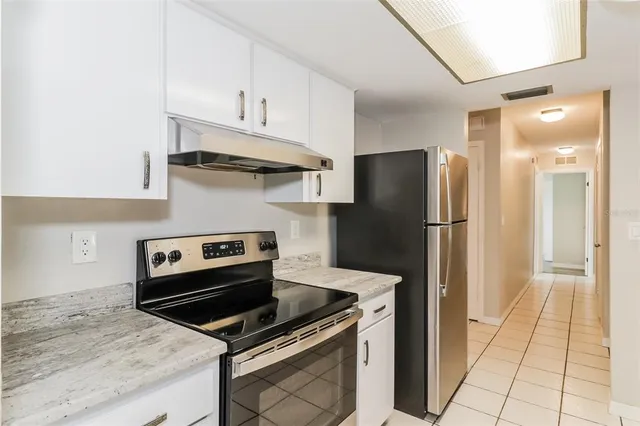 a kitchen with stainless steel appliances granite countertop a refrigerator and a stove top oven