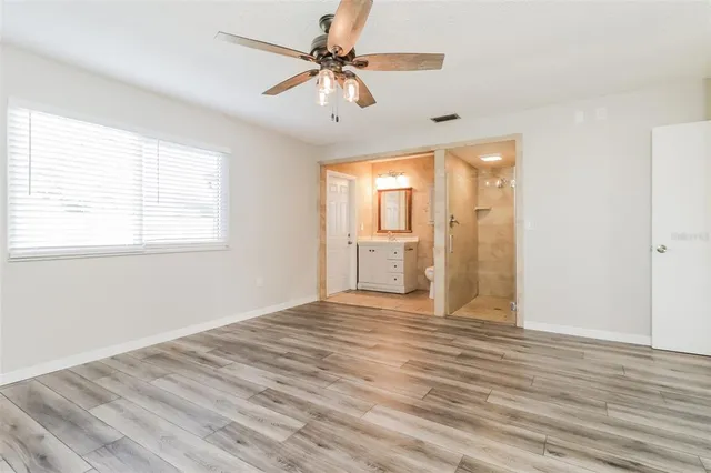 a view of empty room with wooden floor and fan