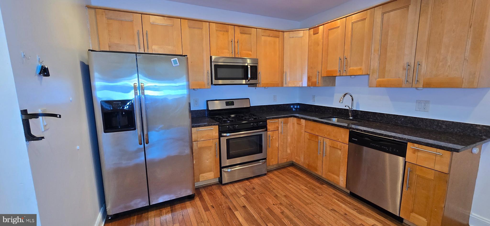 a kitchen with stainless steel appliances granite countertop a stove a sink and a refrigerator
