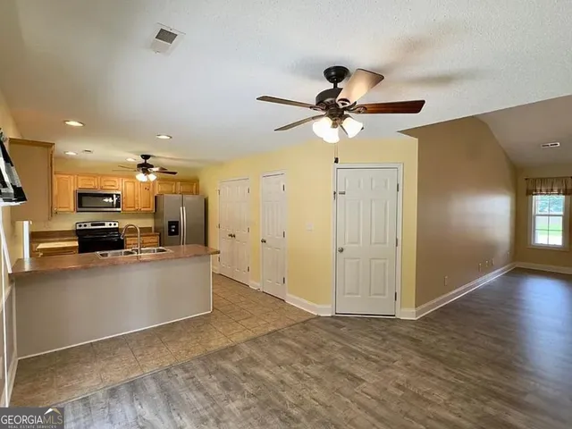 a kitchen with stainless steel appliances kitchen island a refrigerator sink and white cabinets