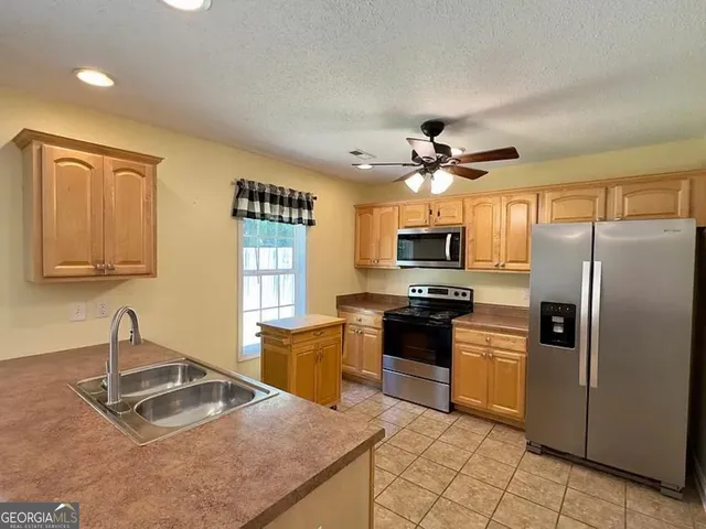 a kitchen with granite countertop a sink stainless steel appliances and cabinets