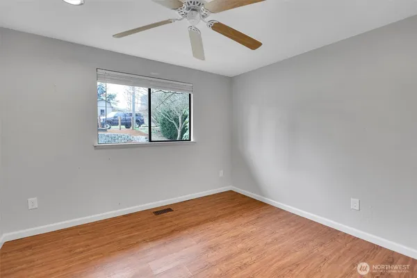 an empty room with wooden floor chandelier fan and windows