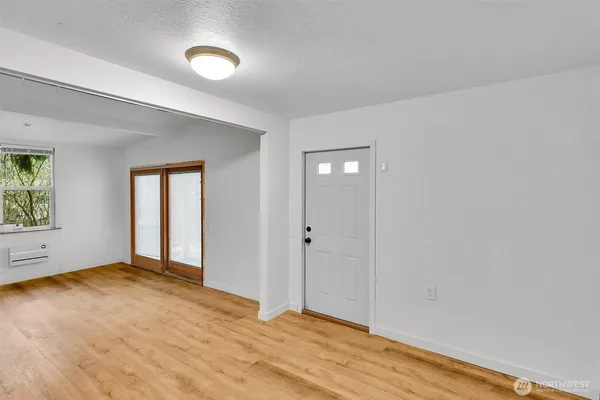 a view of an empty room with wooden floor and window