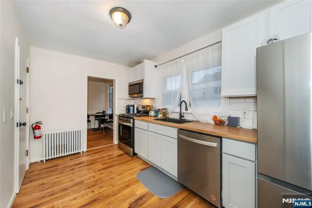 a kitchen with a sink dishwasher stove and white cabinets with wooden floor