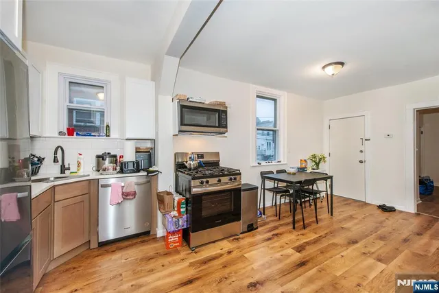 a kitchen with granite countertop a stove top oven a sink dishwasher a dining table and chairs with wooden floor