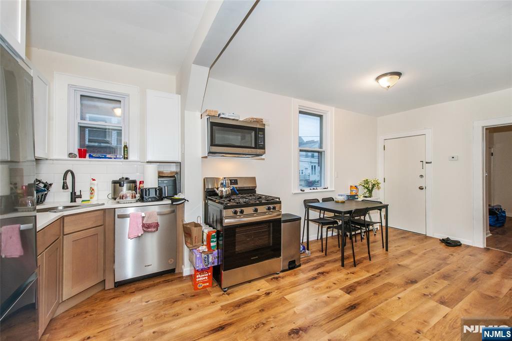 89 King Street Nutley, NJ 07110 - Photo 17 of 32 a kitchen with granite countertop a stove top oven a sink dishwasher a dining table and chairs with wooden floor