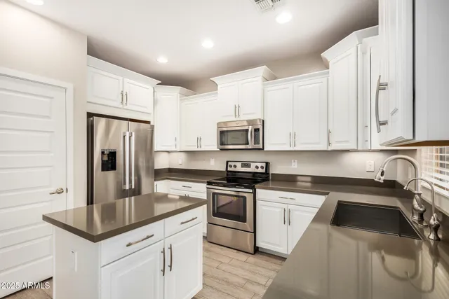 a kitchen with white cabinets and stainless steel appliances