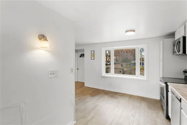 a view of an empty room with a window and wooden floor