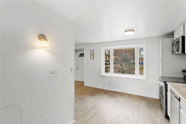 a view of an empty room with a window and wooden floor