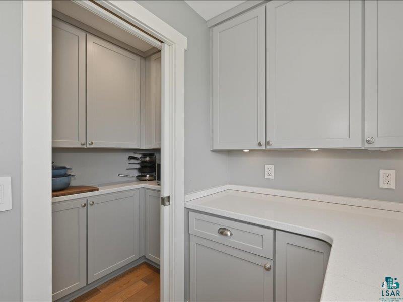 88440 Huron Street Cornucopia, WI 54827 - Photo 10 of 44 Corner pantry with light gray cabinetry, plenty of countertop, and wood-finish flooring