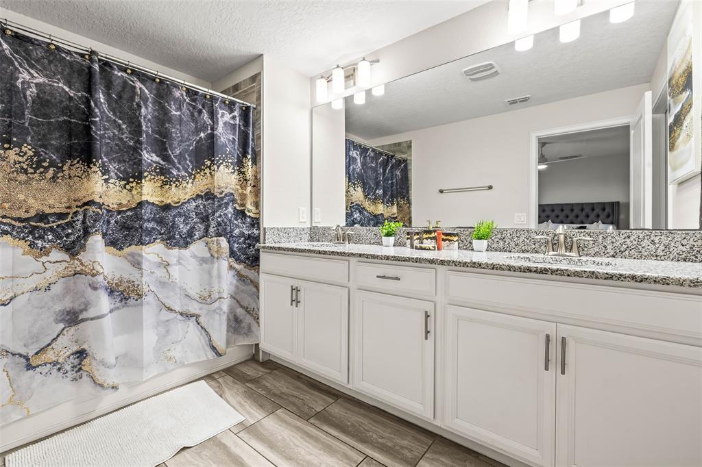 4895 Romeo Circle Kissimmee, FL 34746 - Photo 22 of 93 a bathroom with a granite countertop sink a mirror and shower