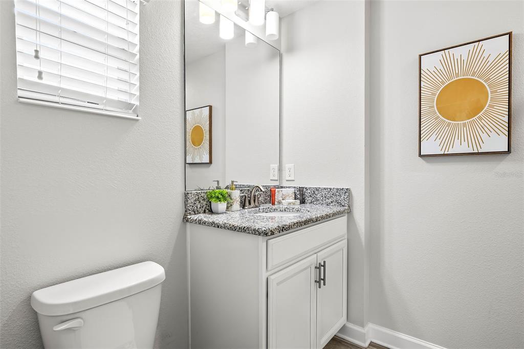 4895 Romeo Circle Kissimmee, FL 34746 - Photo 34 of 93 a bathroom with a granite countertop toilet sink and mirror