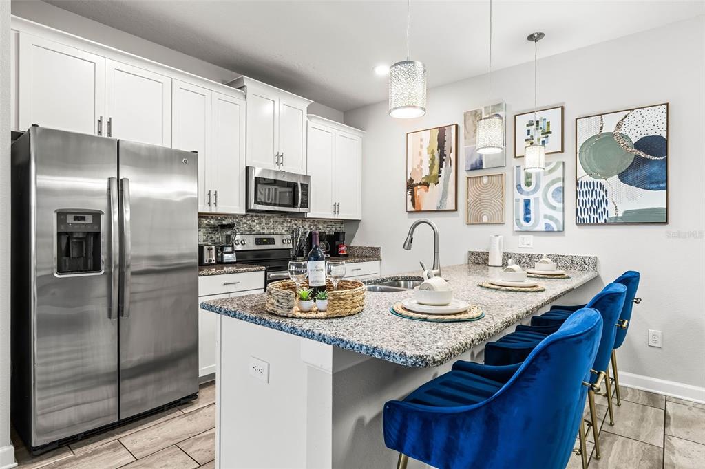 4895 Romeo Circle Kissimmee, FL 34746 - Photo 5 of 93 a kitchen with stainless steel appliances granite countertop a sink a stove a refrigerator cabinets and a dining table