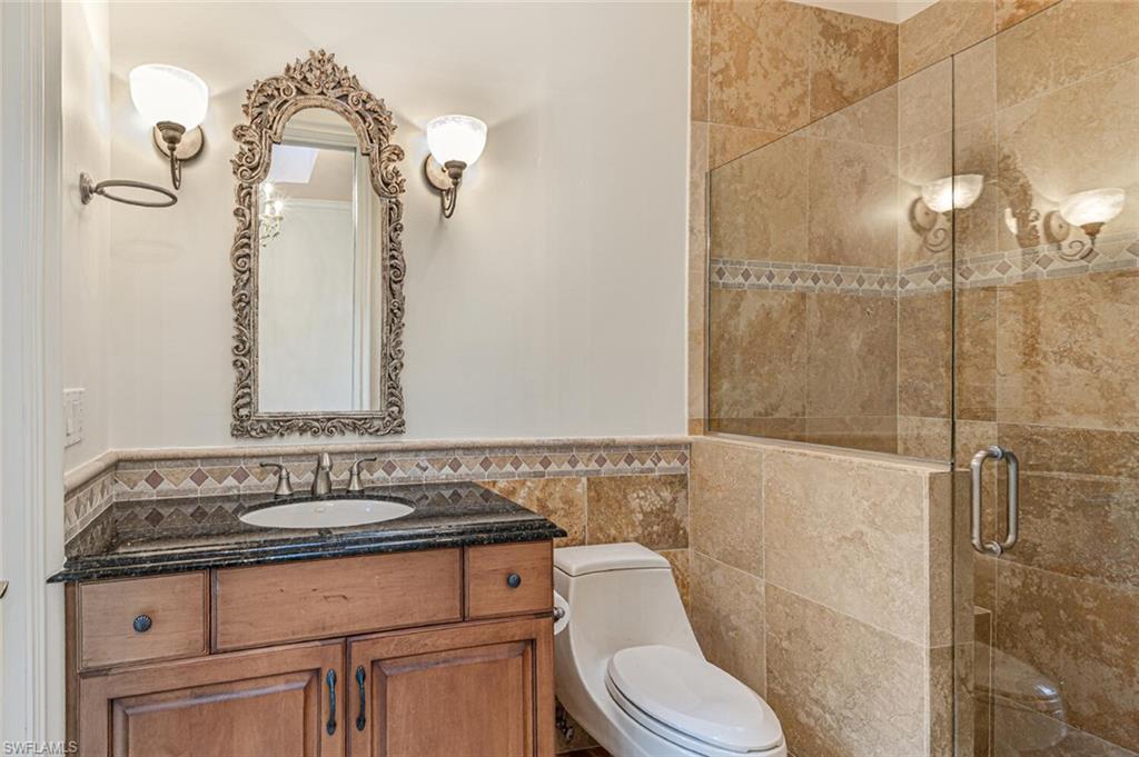 7331 Tilden Lane Naples, FL 34108 - Photo 21 of 50 a bathroom with a granite countertop sink a toilet and a shower