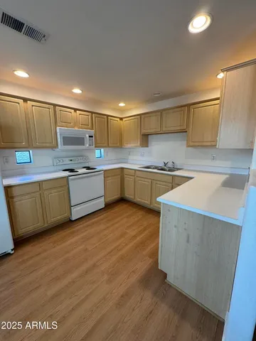 a kitchen with a sink a stove cabinets and wooden floor