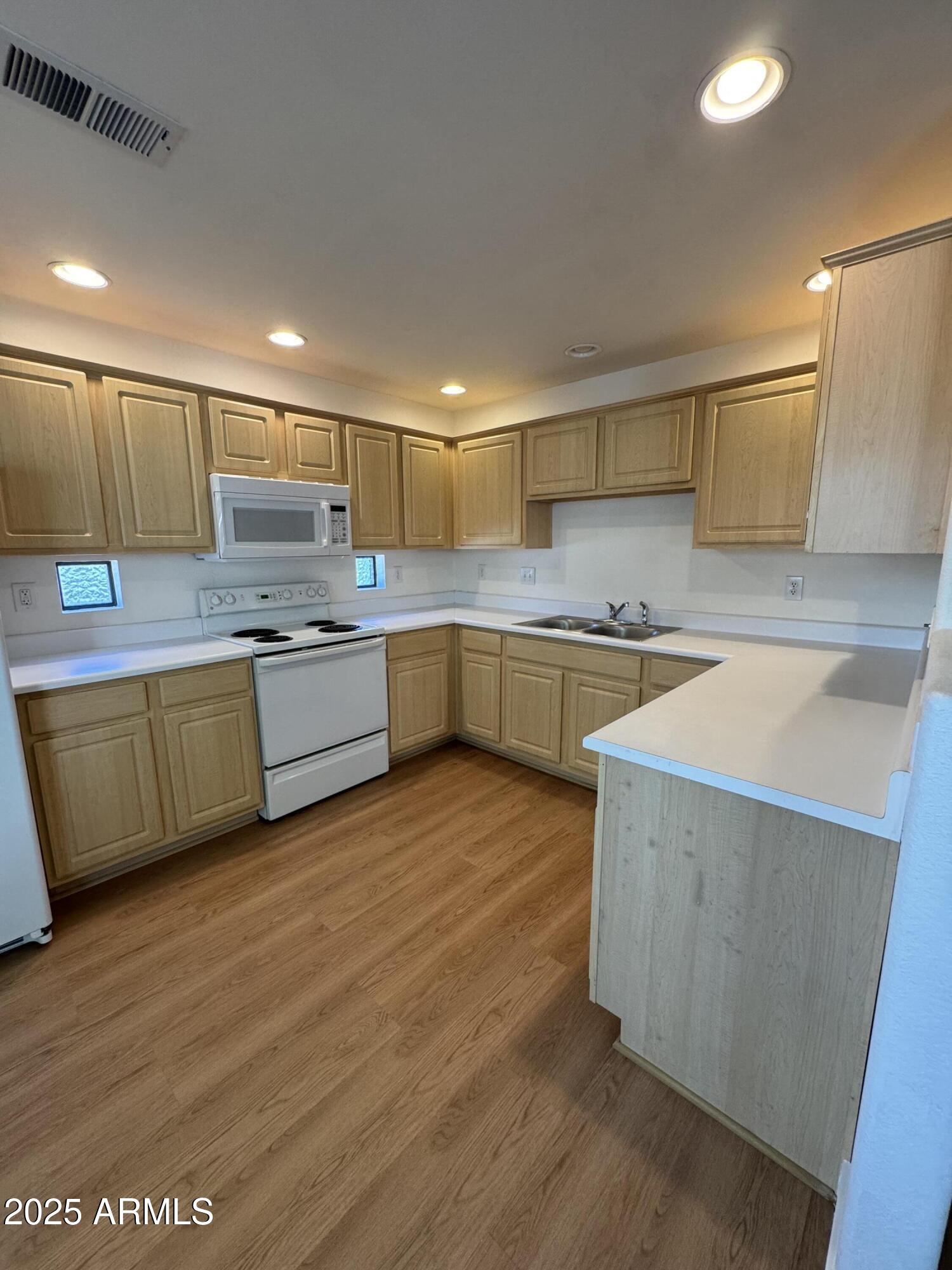 9555 East Raintree Drive, Unit 2008 Scottsdale, AZ 85260 - Photo 11 of 17 a kitchen with a sink a stove cabinets and wooden floor