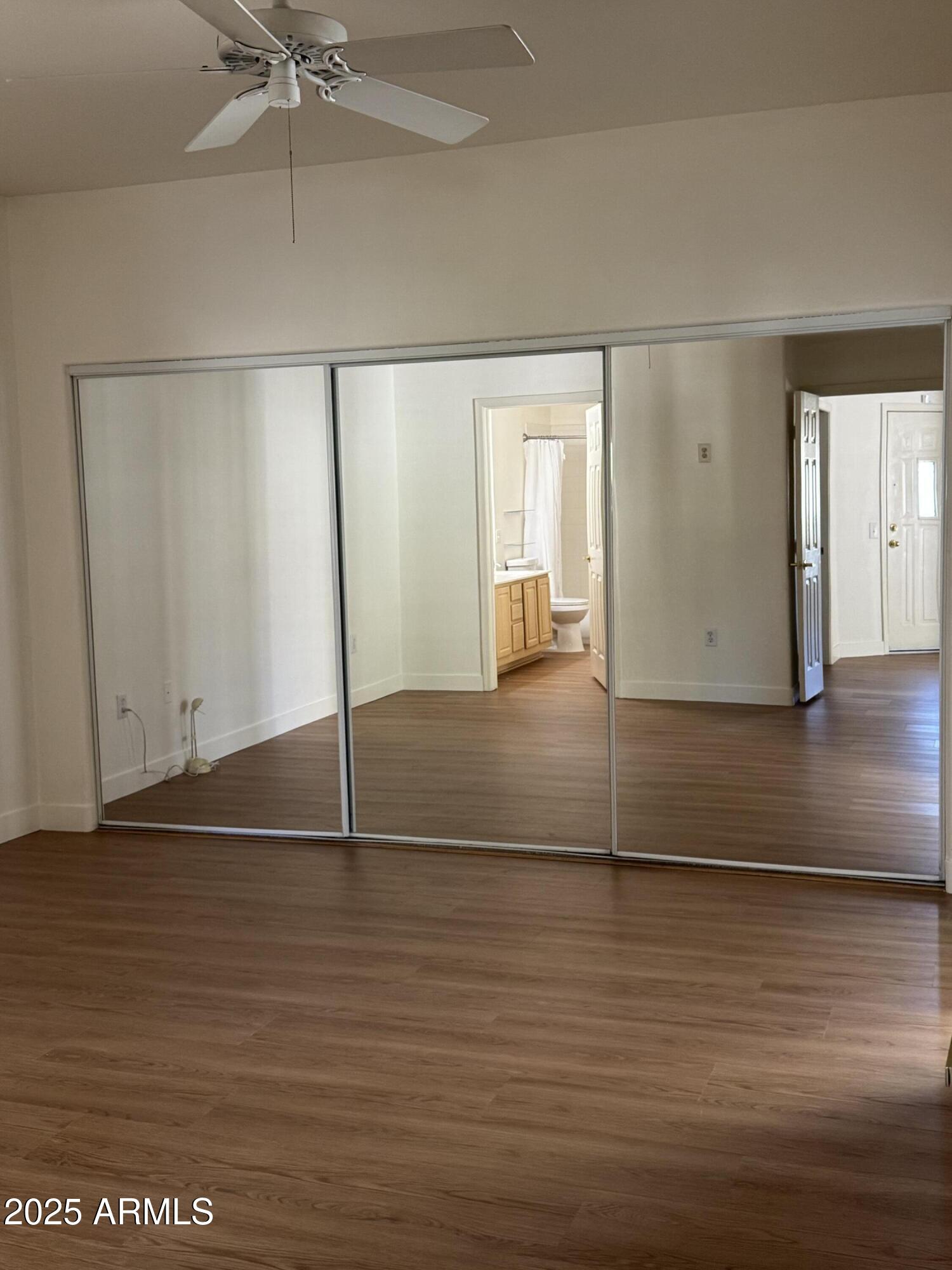 9555 East Raintree Drive, Unit 2008 Scottsdale, AZ 85260 - Photo 5 of 17 an empty room with wooden floor fan and windows