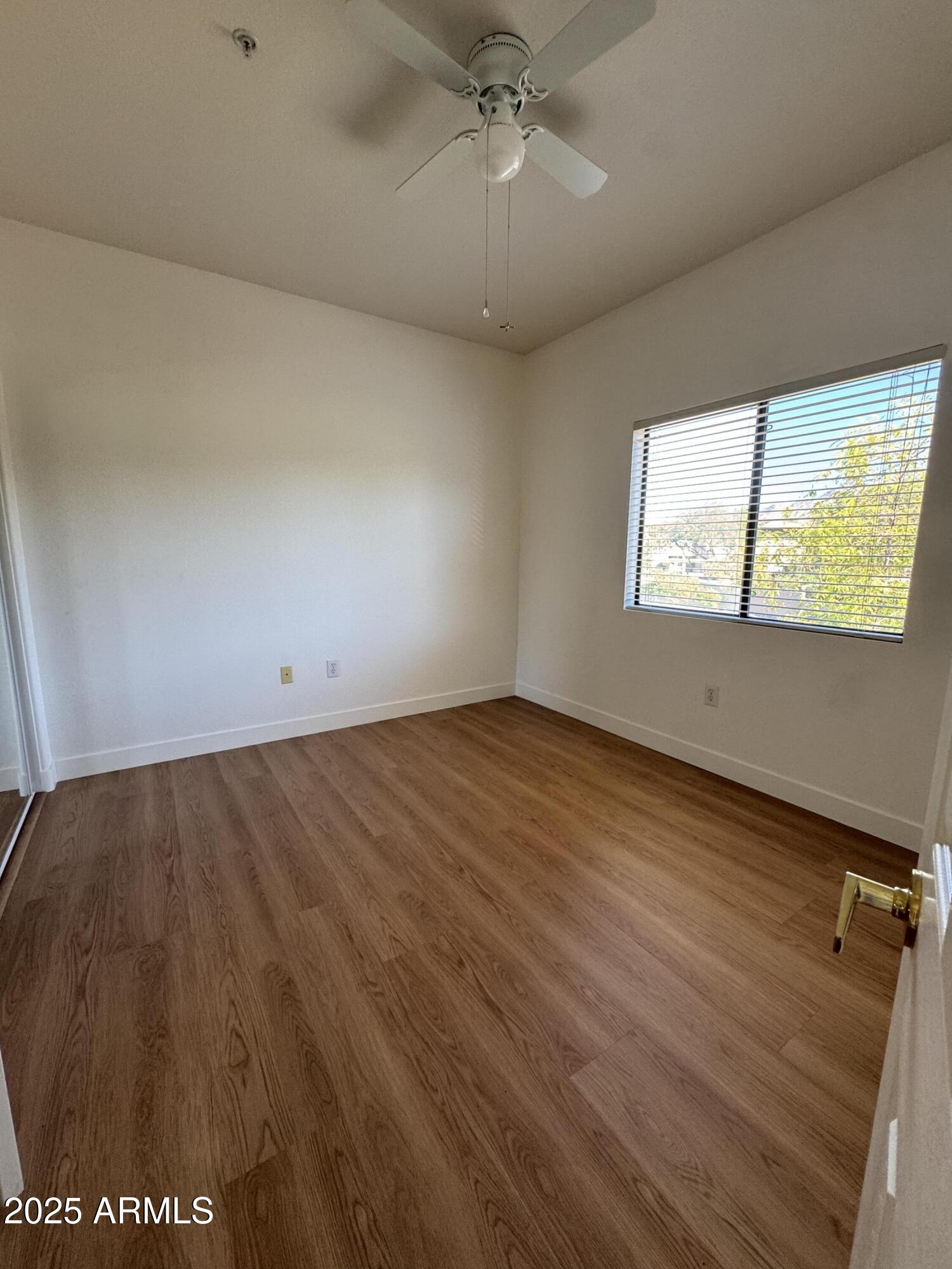 9555 East Raintree Drive, Unit 2008 Scottsdale, AZ 85260 - Photo 7 of 17 an empty room with wooden floor and windows