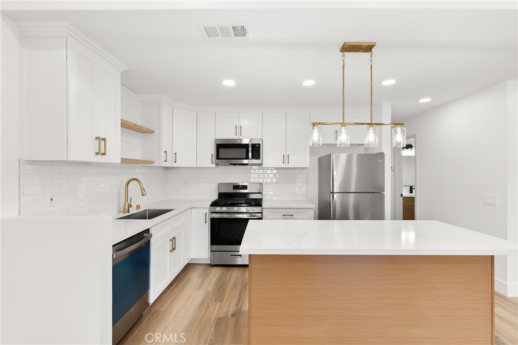 87 Tennessee Street, Unit C Redlands, CA 92373 - Photo 13 of 32 a large kitchen with stainless steel appliances kitchen island granite countertop a refrigerator a sink a stove and white cabinets with wooden floor