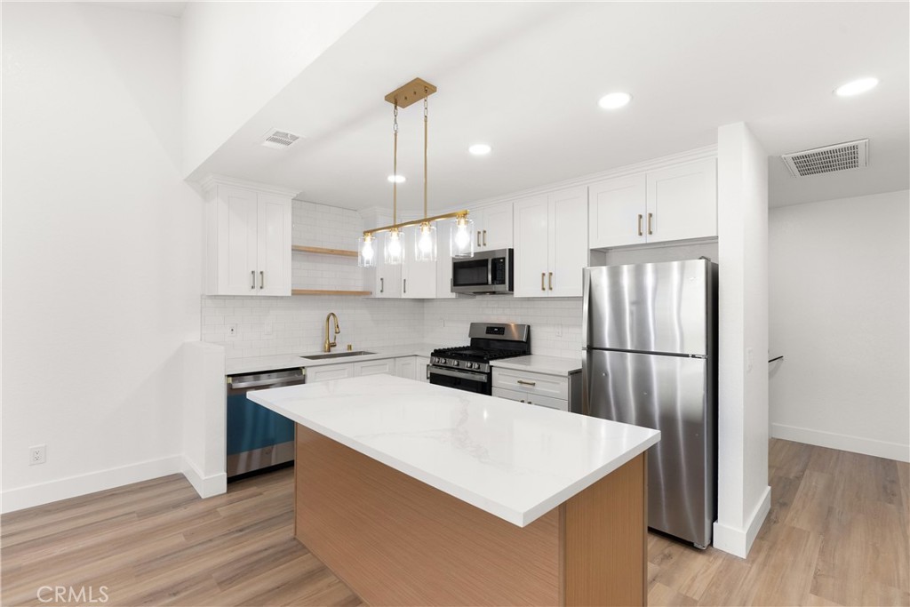 87 Tennessee Street, Unit C Redlands, CA 92373 - Photo 15 of 32 a kitchen with stainless steel appliances a refrigerator a stove a sink dishwasher and a refrigerator with wooden floor