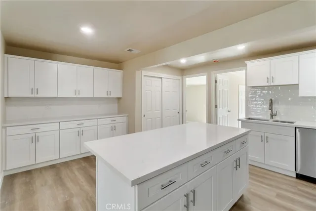 a kitchen with a sink dishwasher a stove and white cabinets with wooden floor