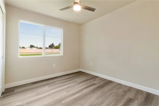 an empty room with wooden floor and fan