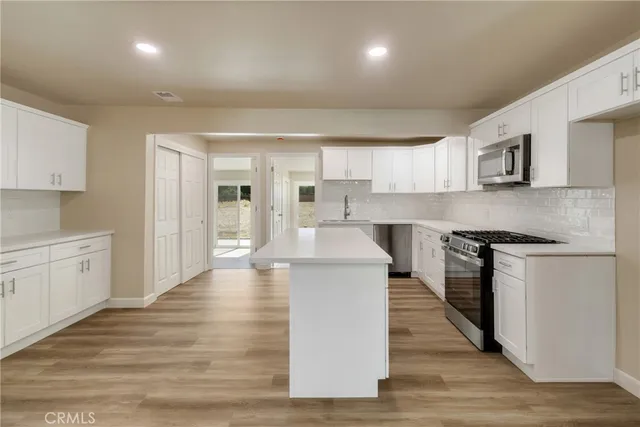 a large kitchen with stainless steel appliances granite countertop a stove a sink and a refrigerator