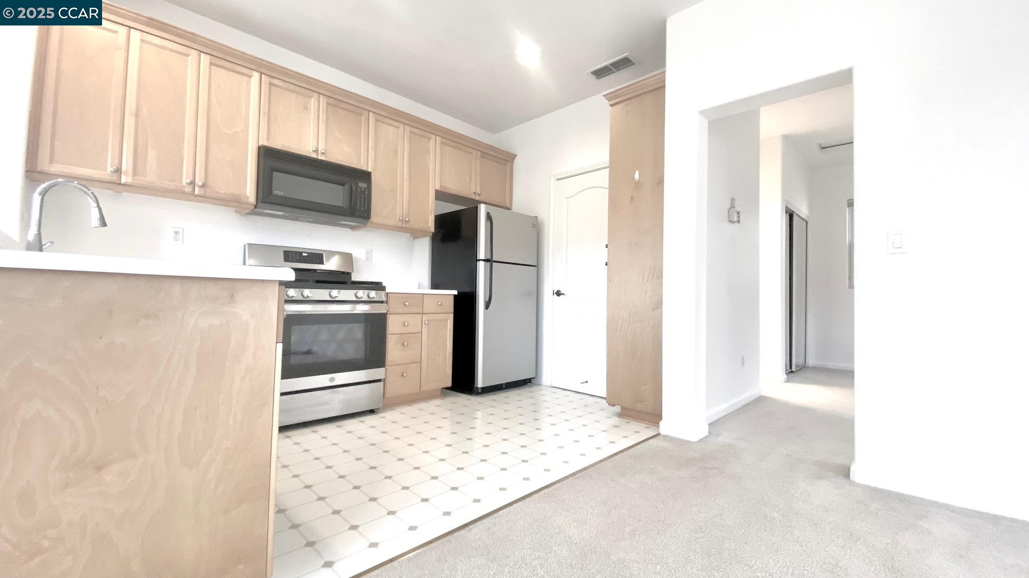 1027 Main Street, Unit B Hercules, CA 94547 - Photo 20 of 39 a kitchen with stainless steel appliances kitchen island granite countertop a refrigerator and a stove top oven