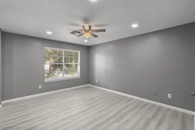 an empty room with wooden floor and windows