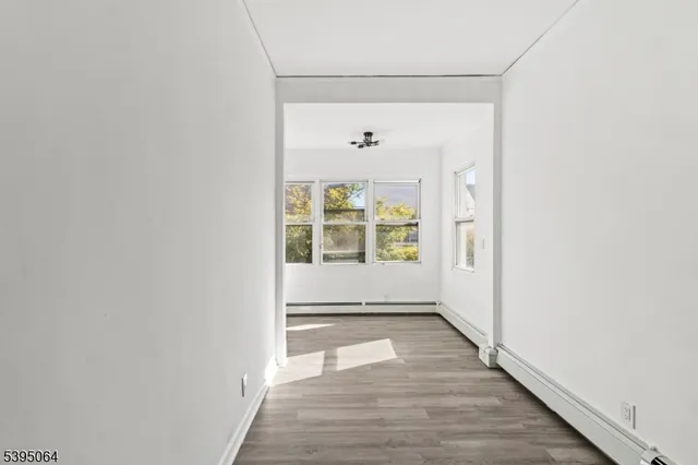 a view of a hallway with wooden floor and a window