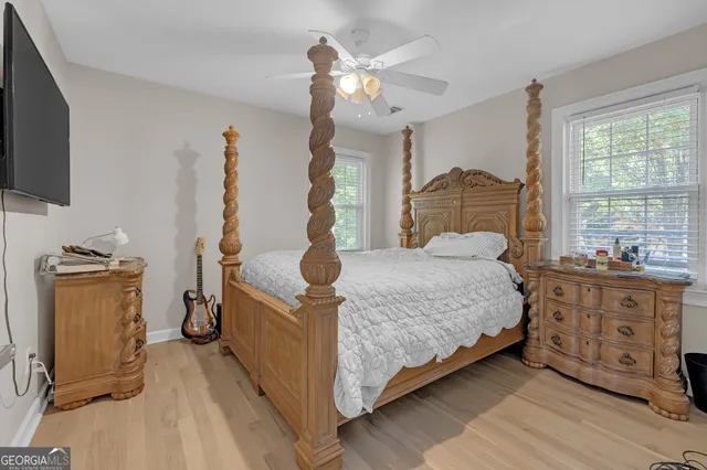 a spacious bedroom with a bed and a flat tv screen on the dresser