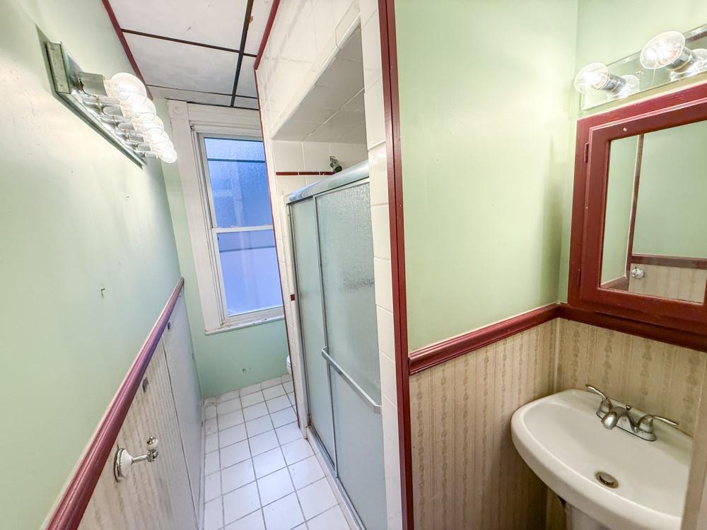 1728 Chislett Street Pittsburgh, PA 15206 - Photo 11 of 16 a bathroom with a sink a mirror and shower