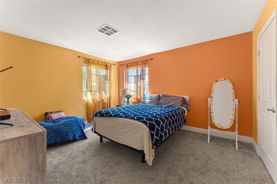 503 Rafkin Place Henderson, NV 89052 - Photo 15 of 18 Two luminous windows frame a carpeted bedroom, offering soft ambient light.