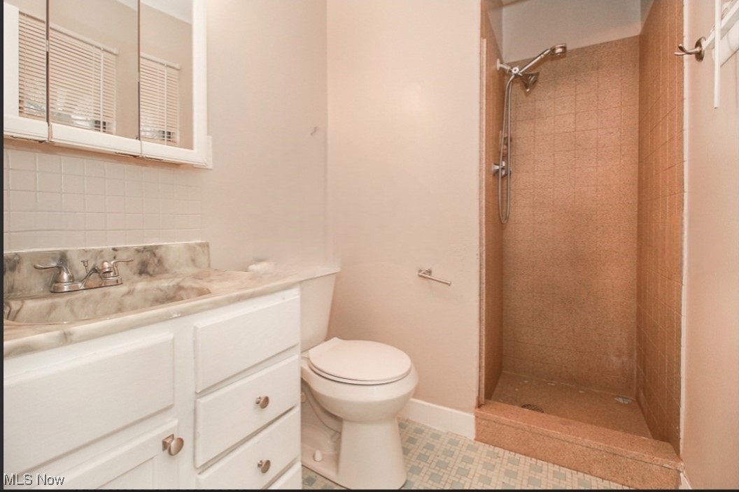 489 Harris Road Cleveland, OH 44143 - Photo 5 of 10 Bathroom with vanity, toilet, tile patterned floors, and tiled shower