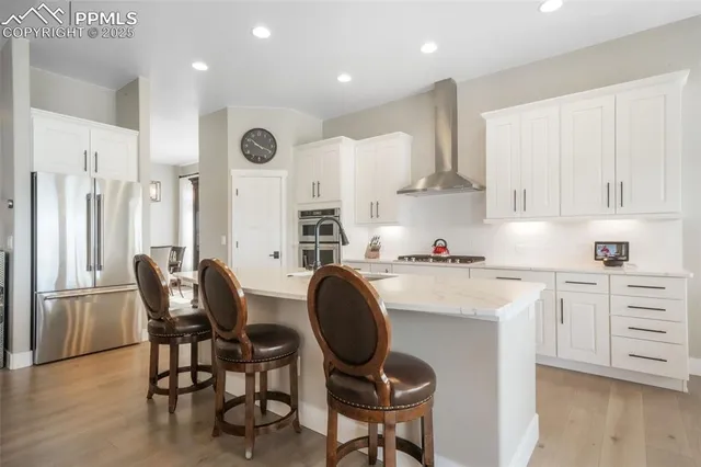 a kitchen with stainless steel appliances granite countertop a table chairs sink and cabinets