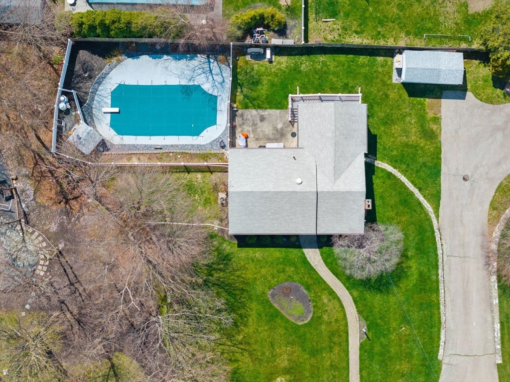 an aerial view of a house with a yard and trees all around