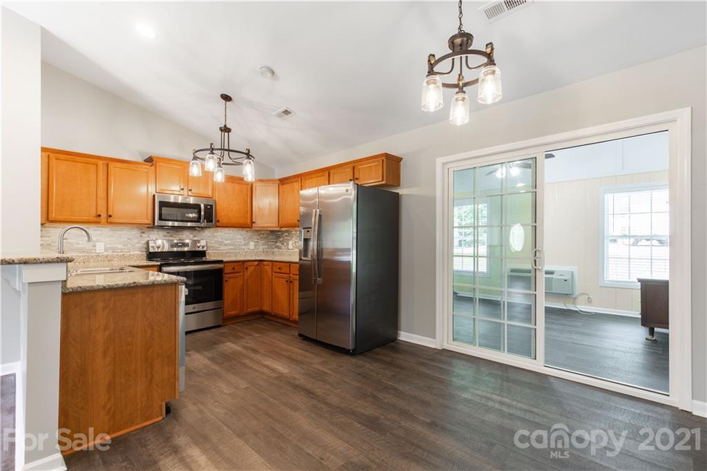 5150 Taxahaw Road Lancaster, SC 29720 - Photo 12 of 27 a kitchen with stainless steel appliances granite countertop a refrigerator a sink dishwasher a stove and white cabinets with wooden floor