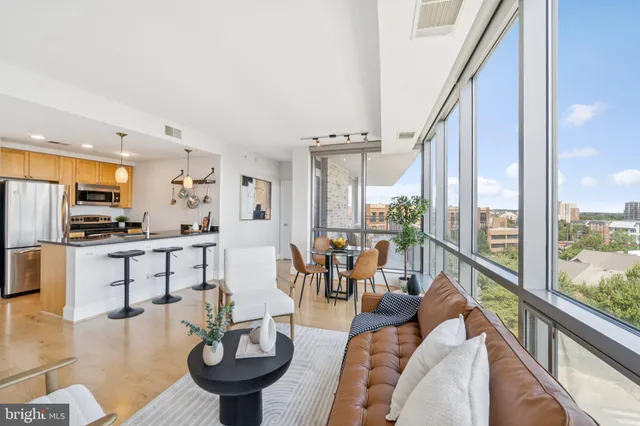 a living room with furniture a large window and kitchen view