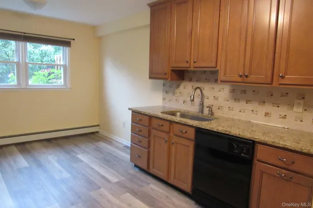 a kitchen with granite countertop wooden cabinets a sink and dishwasher with wooden floor