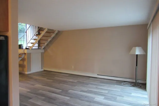 a view of an empty room with wooden floor and stairs