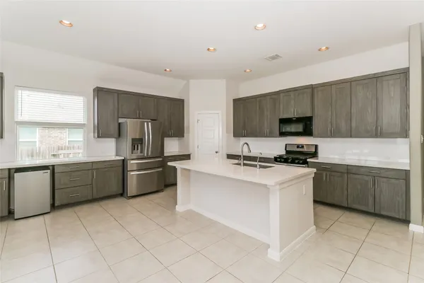 a kitchen with stainless steel appliances granite countertop a stove top oven a sink dishwasher and a refrigerator with white cabinets