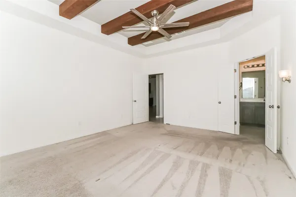an empty room with chandelier fan and windows