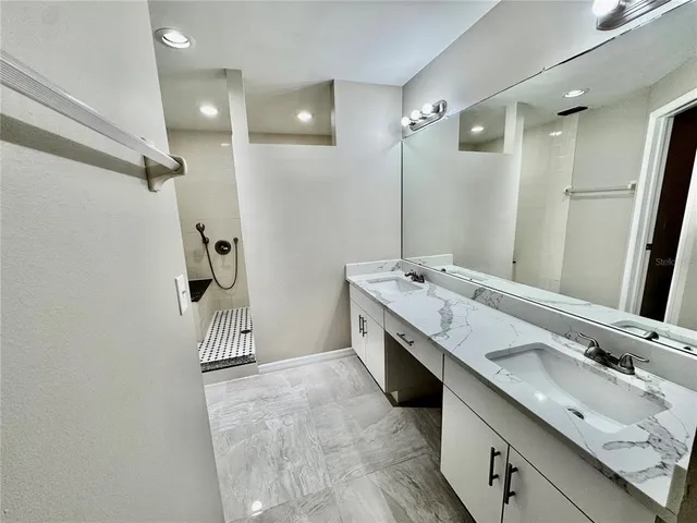a bathroom with a double vanity sink a mirror and shower