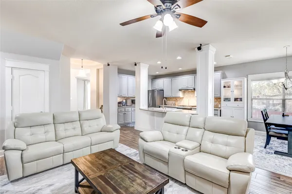 a living room with furniture kitchen area and a chandelier