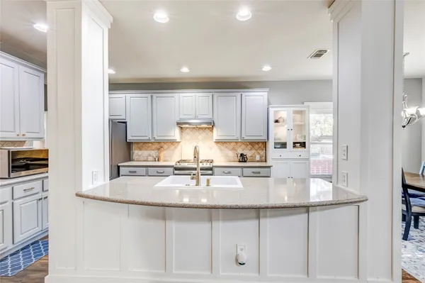 a kitchen with granite countertop white cabinets and stainless steel appliances