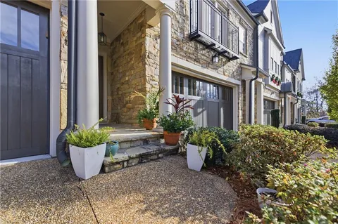 a view of a brick house with potted plants and a bench