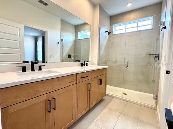 a bathroom with a double vanity sink mirror and shower