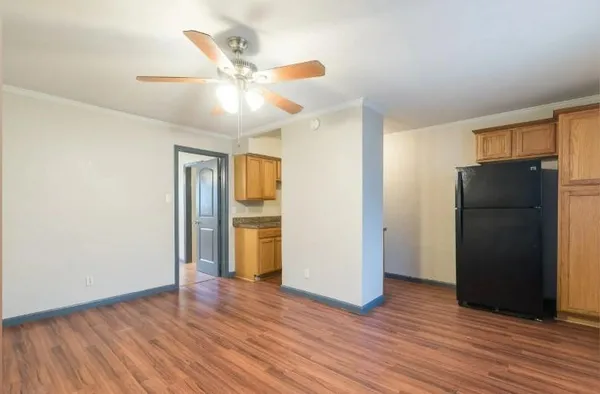 a view of an empty room with wooden floor and a ceiling fan