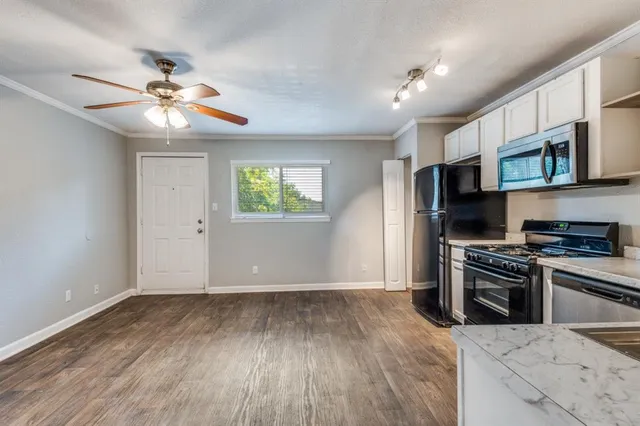 a kitchen with stainless steel appliances granite countertop a stove top oven a refrigerator a sink and dishwasher with wooden floor