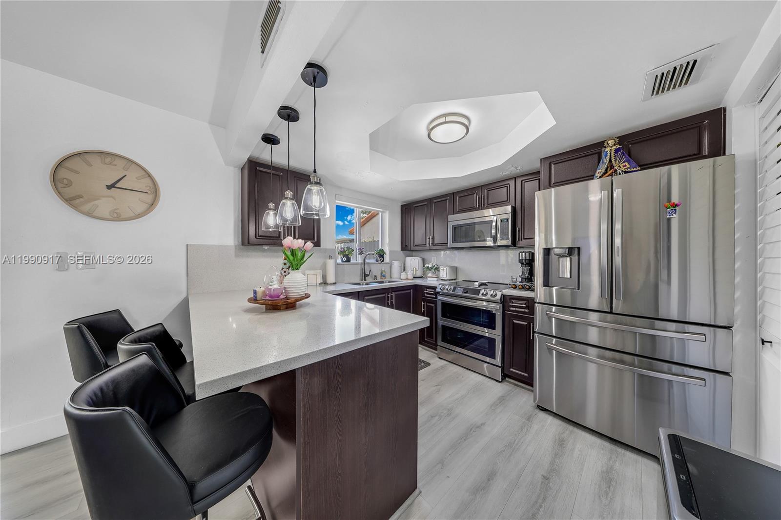 12511 Southwest 12th Lane Miami, FL 33184 - Photo 7 of 20 a kitchen with stainless steel appliances granite countertop a refrigerator a stove a sink a dining table and chairs with wooden floor